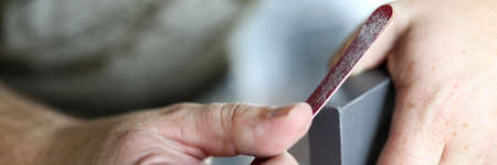 The mans hands are processing the edges of the cabinet door with a nail file. File the edges of furnitureの写真素材