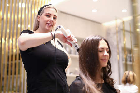 Portrait of smiling woman looking at camera with calmness and gladness. Hairdresser enjoying work....