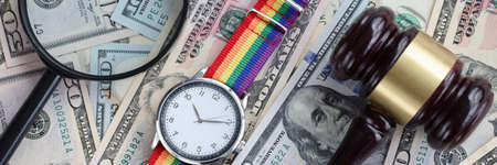 On table are American banknotes magnifying glass lgbt watch and wooden gavel. Sexual minority rights conceptの写真素材