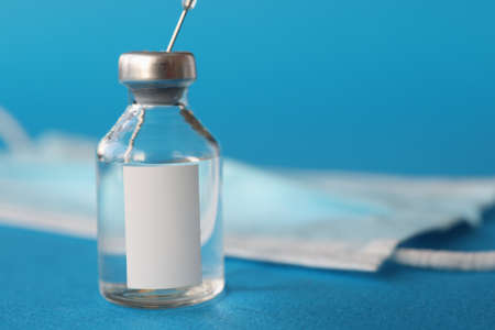 Glass bottle with medicine standing near medical protective mask in clinic closeup. Prevention...