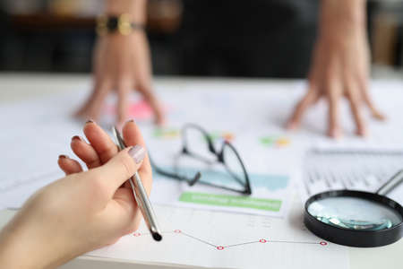 Hands hold pen on table are commercial charts and magnifying glass. Small and medium business...