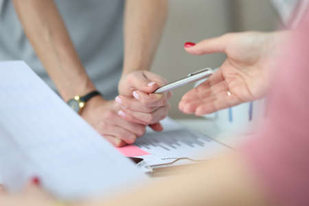 Above work table, hands and a pen on table are charts with business figures. Business development...