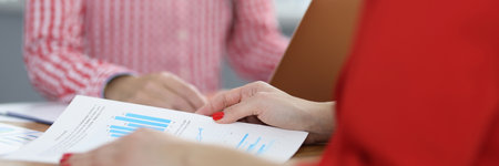 Two businesswomen at work table discussing charts with commercial indicators. Small and medium business development conceptの写真素材