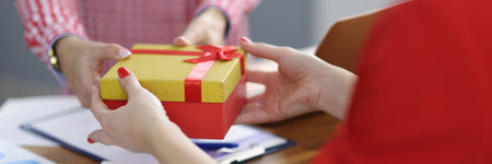 Businesswoman gives gift to colleague at workplace. Gifts in workplace concept