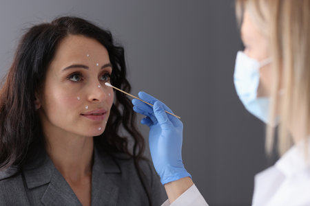 Beautician applies white cream to patients face with cotton swab. Facial procedures conceptの写真素材
