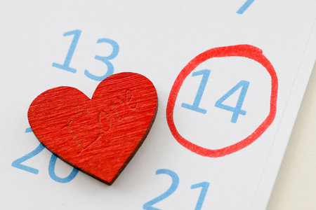 Number 14 circled in red pen on calendar near toy heart. Celebrating Valentines Day conceptの写真素材