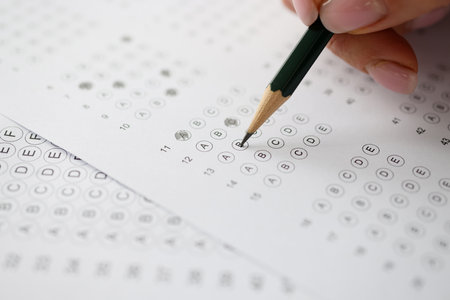 Woman solving tests and writing in pencil on paper closeup. Exam testing conceptの写真素材