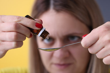 Woman dripping drops from medicine bottle closeup. Liquid forms of drugs conceptの写真素材