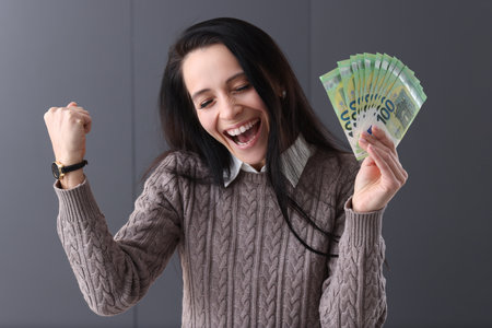 Joyful woman holds euro in her hand. Remote work and gambling conceptの写真素材