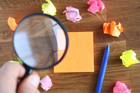 Hand holding magnifying glass over orange sticker closeupの写真素材