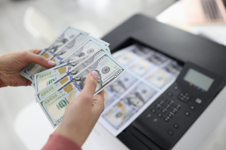 Woman printing dollar bills on printer closeup. Counterfeiting money concept