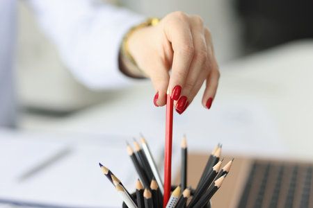 Female hand with red nails holds red pencil. Correct decision in management conceptの写真素材