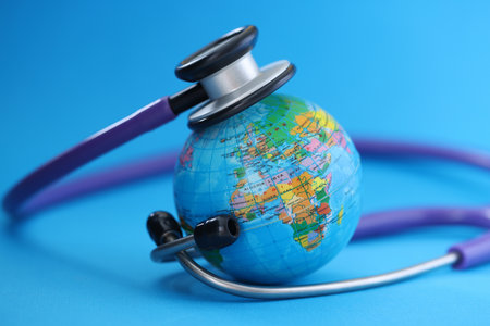 Stethoscope lying around globe on blue background.の写真素材