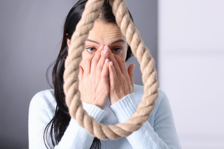 Young woman standing in front of noose of rope and crying. Suicide prevention conceptの写真素材