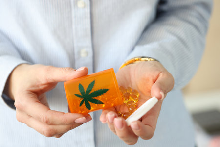 Female hands hold jar of marijuana pills. Medicinal properties of marijuana conceptの写真素材