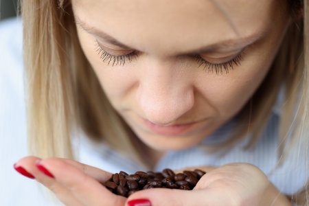 Woman is sniffing coffee grains on her palm. How to distinguish real coffee from fake conceptの写真素材