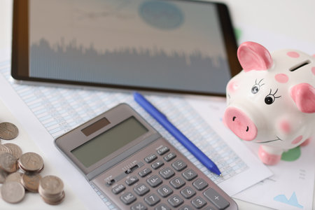 On table is calculator pig and tablet with coins. Advantageous offers on deposits conceptの写真素材