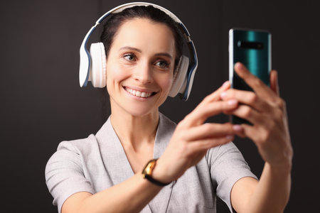 Smiling woman in headphones looks into smartphone. Social media blog introduction concept