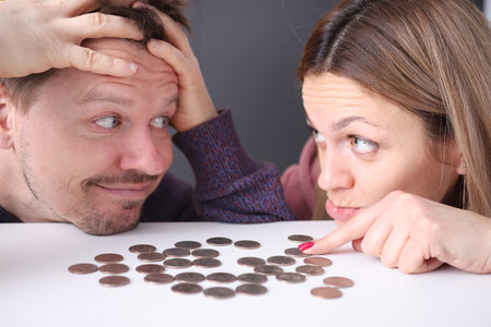 Man and woman look at coins in frustration. Family budget planning concept