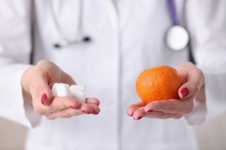Doctor holding orange and sugar cubes in his hands closeup. Prevention of diabetes conceptの写真素材