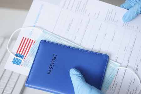 Hands in rubber gloves holding passport and documents for US visa closeup. Difficulty traveling...
