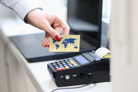 Female hand holding credit bank card near pos terminal closeup.の写真素材