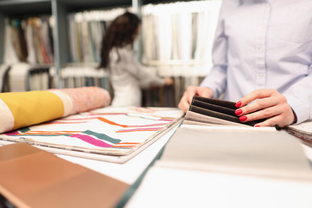 Woman shopper choosing curtain fabric sample in store closeup. Selection and sale of fabrics conceptの写真素材
