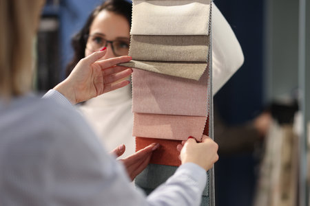 Seller and buyer choosing fabrics for curtains in catalog closeup. Design work concept