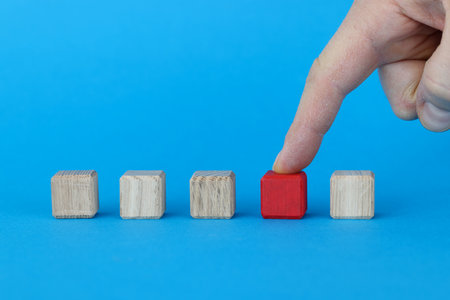 Index finger standing on red cube among other cubes closeup. Choice of business strategy conceptの写真素材