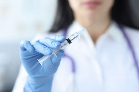 Doctor in rubber gloves holding syringe with medicine closeup. Vaccine prophylaxis conceptの写真素材