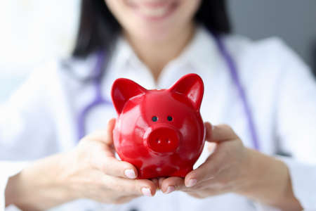 Doctor holds piggy bank in his hands. Health insurance and payments conceptの写真素材