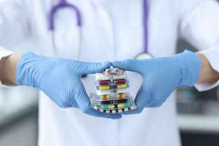 Doctor with gloves holds medications. Uncontrolled use of medicines conceptの写真素材