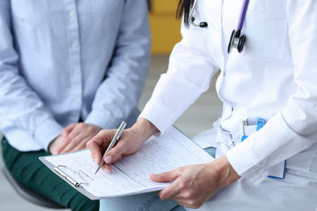 Doctor writes down patients health symptoms on card. First signs of health problems conceptの写真素材
