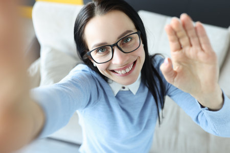 Smiling brunette woman with glasses looking at camera. How to take a selfie concept correctlyの写真素材