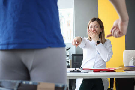 Doctor laughingly looks at male patient with his pants removed. Male potency problems conceptの写真素材