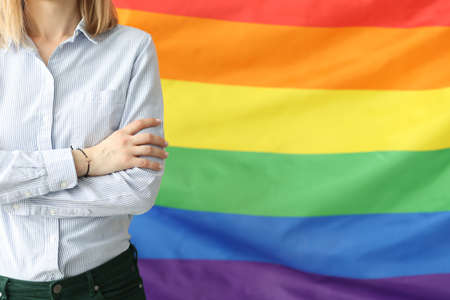 Woman stands with folded arms against background of lgbt flag. Reasons for same sex love conceptの写真素材