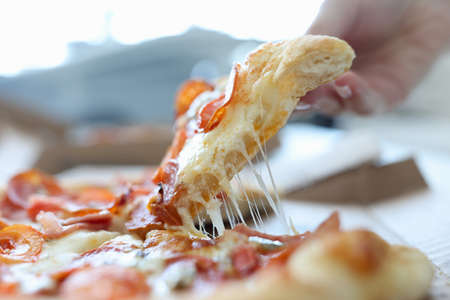 Womans hand takes piece of cheese pizza. Useful properties of pizza concept