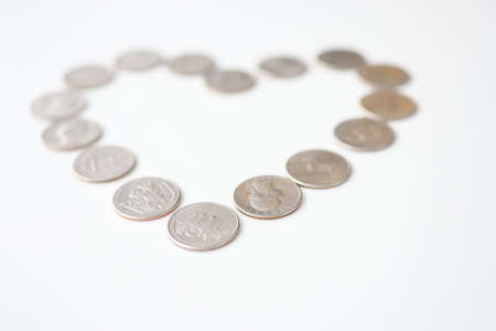 Silver coins lying in shape of heart on white background. Love of money conceptの写真素材