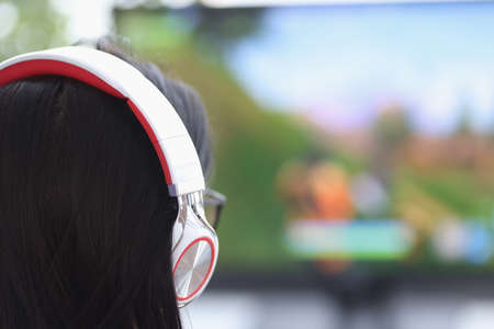 Woman with headphones sitting at computer screen. Entertainment and recreation concept