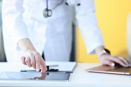 Doctor working on digital tablet at workplace closeup. Remote patient consultation conceptの写真素材