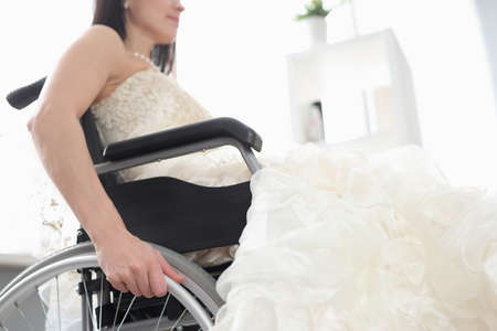 Woman in wedding dress is sitting in wheelchair. Family life for people with disabilities conceptの写真素材