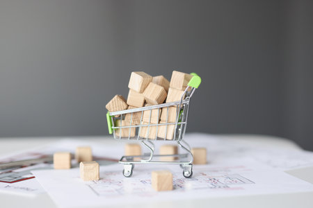 Many wooden cubes lying in toy shopping car closeup. Housing construction conceptの写真素材