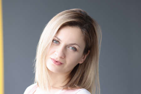 Portrait of young blonde woman on gray background. Skin care concept
