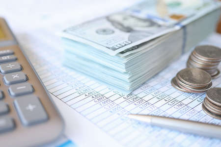 Dollar bills and coins lying on documents with numbers closeup. Illegal accounting concept