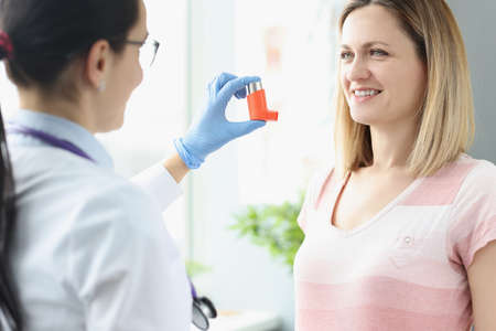 Woman holds an asthma inhaler in her hand. Treatment of bronchial asthma conceptの写真素材