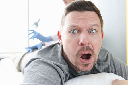 Doctor gives an injection to frightened man. Trypanophobia fear of injections, injections and syringes conceptの写真素材
