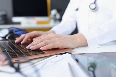 Doctors hands on laptop keyboard. Remote medical assistance closeupの写真素材