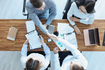 Business people at their desk shake hands in handshake. businessの写真素材