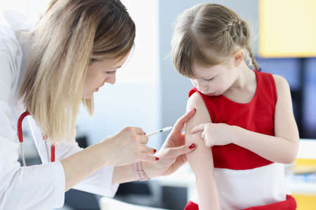 Doctor gives little girl shot in shoulderの写真素材
