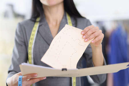 Woman seamstress holding in her hand sketch for production of clothes closeupの写真素材